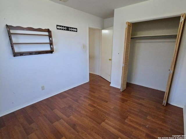 unfurnished bedroom featuring dark hardwood / wood-style floors and a closet