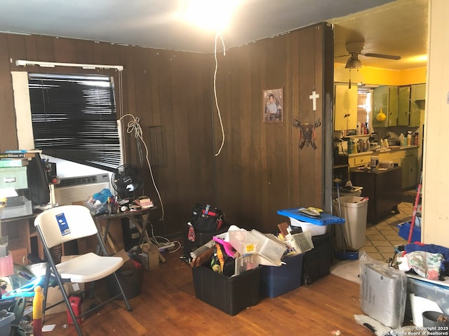 miscellaneous room featuring dark hardwood / wood-style flooring, ceiling fan, cooling unit, and wood walls