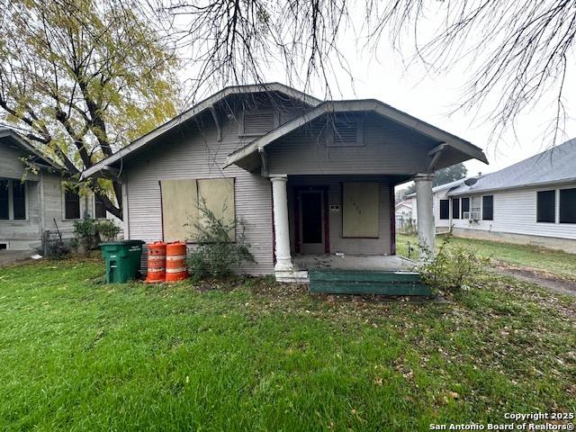 back of house featuring covered porch and a lawn