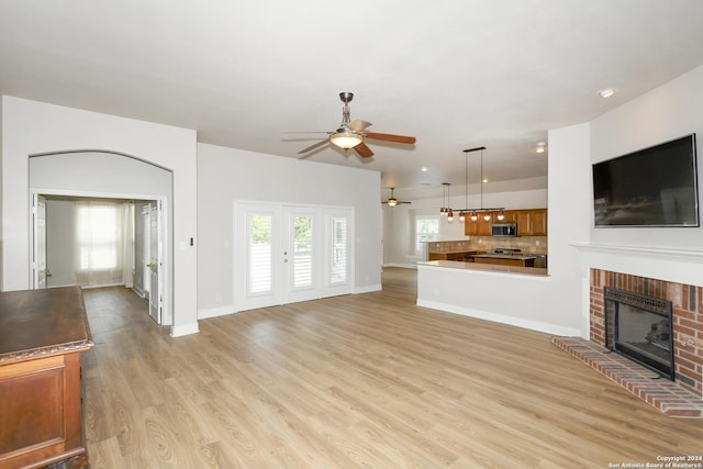 unfurnished living room featuring light hardwood / wood-style floors, a brick fireplace, plenty of natural light, and ceiling fan