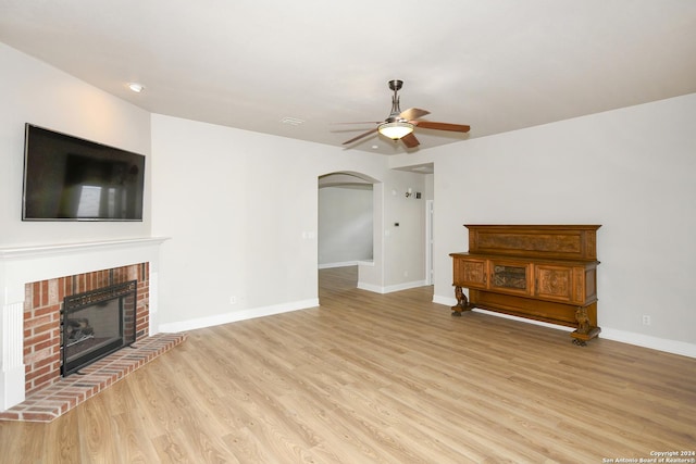 unfurnished living room featuring light hardwood / wood-style flooring, a brick fireplace, and ceiling fan