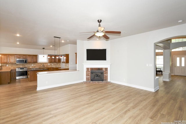 unfurnished living room featuring ceiling fan, a fireplace, and light hardwood / wood-style floors