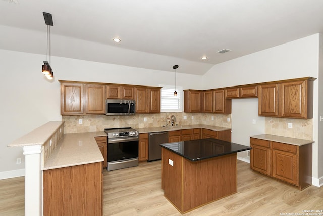 kitchen with kitchen peninsula, appliances with stainless steel finishes, sink, pendant lighting, and lofted ceiling