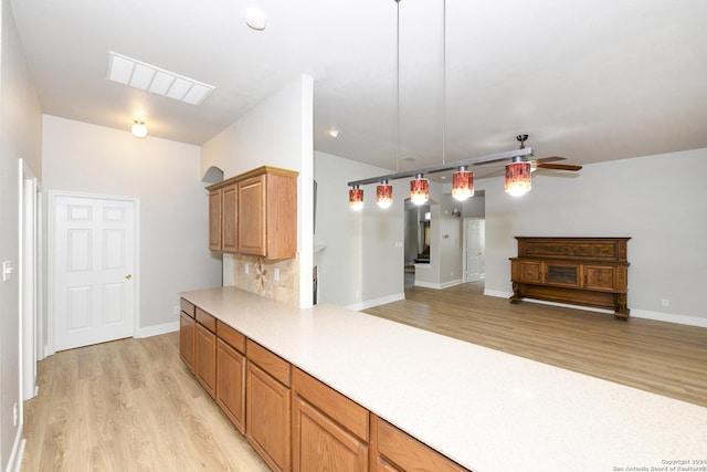 kitchen featuring pendant lighting, backsplash, light hardwood / wood-style floors, and ceiling fan