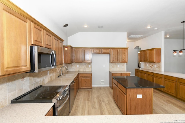 kitchen with appliances with stainless steel finishes, tasteful backsplash, sink, light hardwood / wood-style flooring, and hanging light fixtures