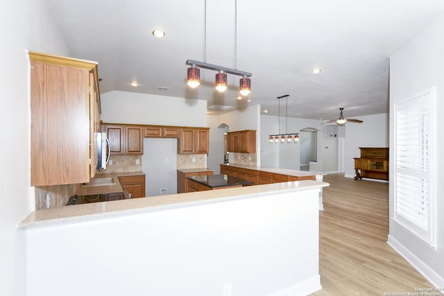 kitchen featuring decorative backsplash, ceiling fan, kitchen peninsula, and hanging light fixtures