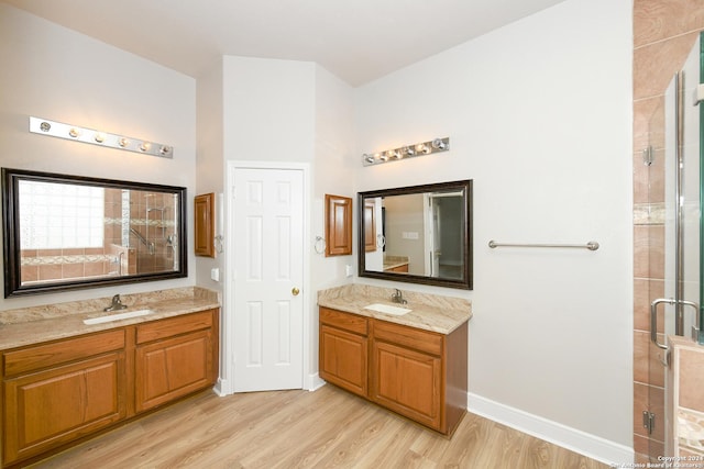 bathroom with hardwood / wood-style floors, vanity, and a shower with door