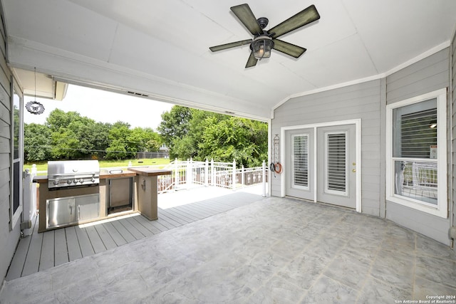 wooden terrace featuring a grill, ceiling fan, and exterior kitchen