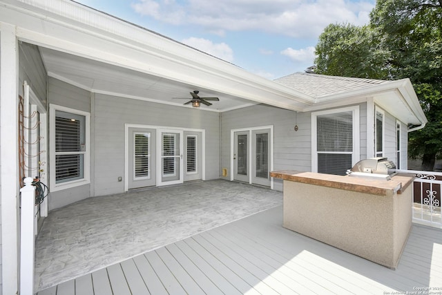 wooden deck featuring ceiling fan, area for grilling, and exterior kitchen