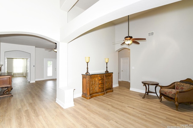 sitting room featuring ceiling fan, light hardwood / wood-style floors, and a high ceiling