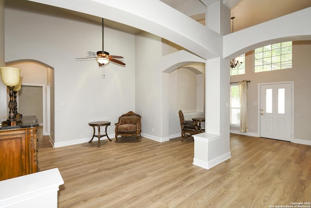 foyer featuring ceiling fan, light hardwood / wood-style floors, and a high ceiling