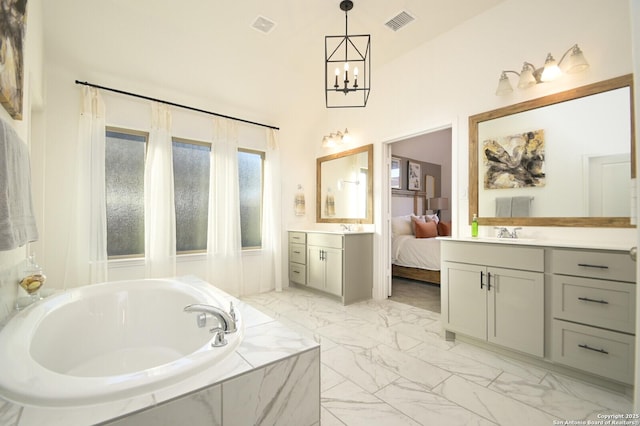 bathroom with vanity, a relaxing tiled tub, and a notable chandelier