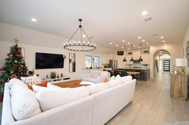 living room with plenty of natural light, a chandelier, and light wood-type flooring