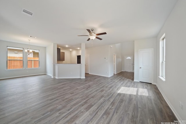 unfurnished living room with plenty of natural light, wood-type flooring, and ceiling fan with notable chandelier