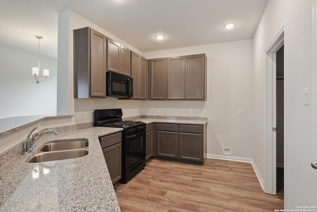 kitchen featuring light stone countertops, dark brown cabinetry, sink, black appliances, and pendant lighting