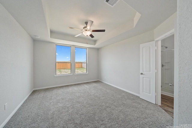 carpeted empty room with a raised ceiling and ceiling fan