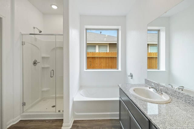 bathroom with hardwood / wood-style floors, vanity, and independent shower and bath