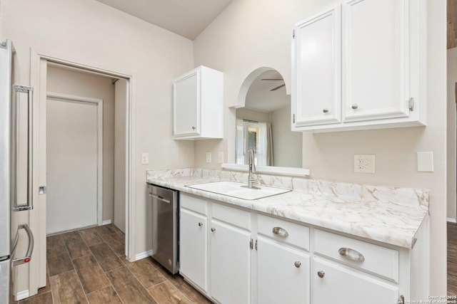 kitchen featuring light stone countertops, refrigerator, white cabinets, stainless steel dishwasher, and sink