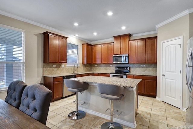 kitchen with light stone counters, stainless steel appliances, a center island, a breakfast bar area, and light tile patterned flooring