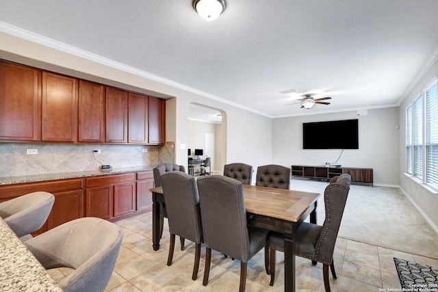 tiled dining room featuring ceiling fan and crown molding