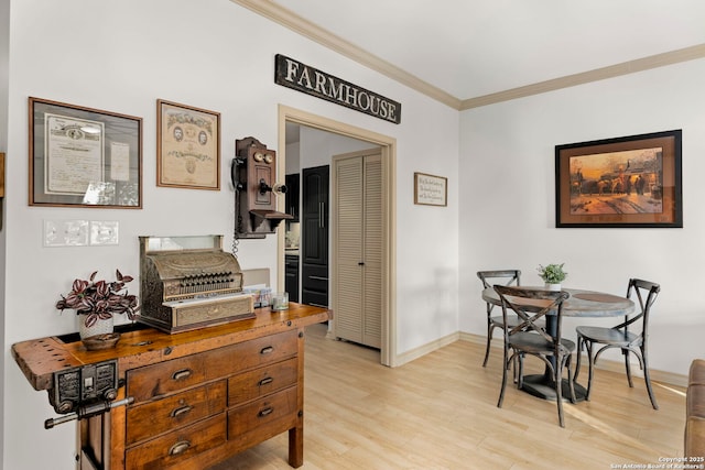 dining space with ornamental molding and light hardwood / wood-style flooring