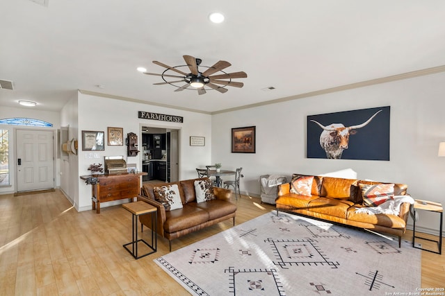 living room featuring ceiling fan, light wood-type flooring, and ornamental molding