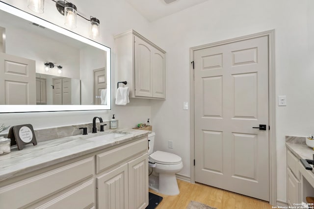 bathroom with toilet, vanity, and hardwood / wood-style flooring