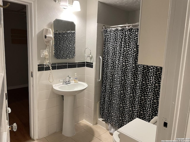 bathroom featuring a shower with curtain, a textured ceiling, tile walls, tile patterned flooring, and toilet