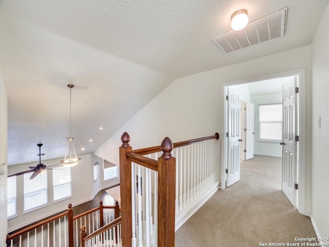 hall with light carpet, a wealth of natural light, and lofted ceiling