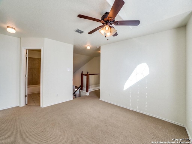 empty room with ceiling fan, light colored carpet, and lofted ceiling