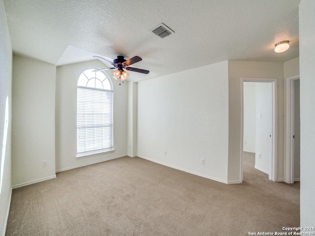 carpeted empty room featuring a textured ceiling, ceiling fan, and vaulted ceiling