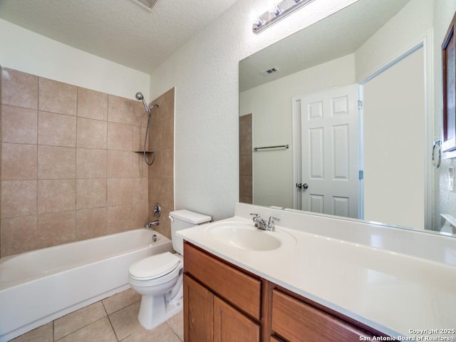 full bathroom featuring vanity, tiled shower / bath, tile patterned flooring, toilet, and a textured ceiling