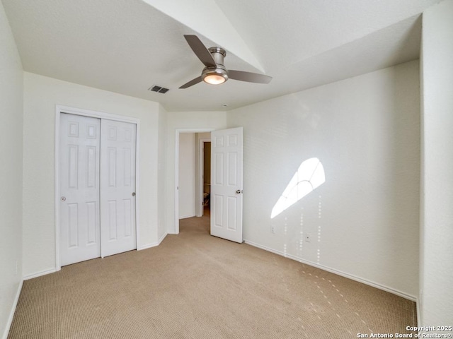 unfurnished bedroom with light colored carpet, a closet, and ceiling fan