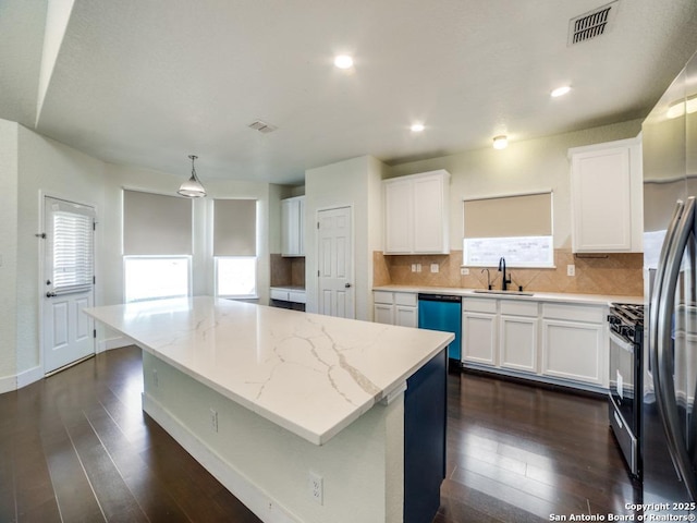 kitchen with sink, a kitchen island, light stone counters, pendant lighting, and white cabinets