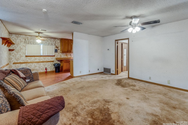 living room with ceiling fan, light colored carpet, and a textured ceiling