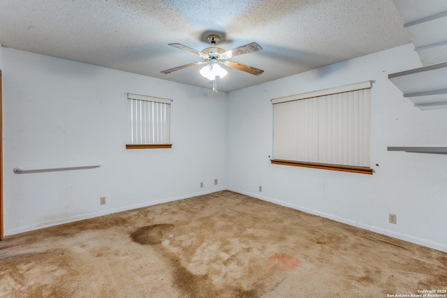 empty room featuring ceiling fan, light colored carpet, and a textured ceiling