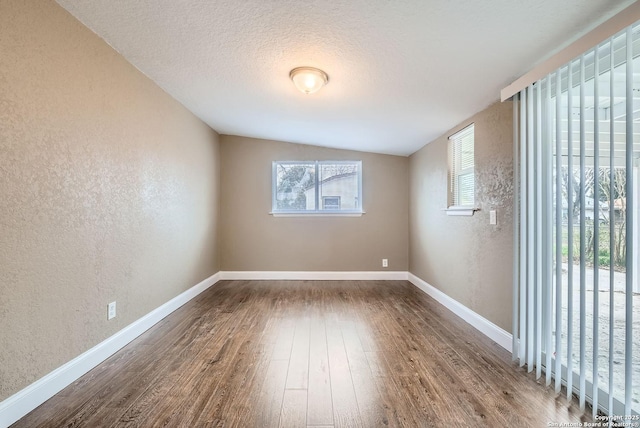 spare room featuring wood-type flooring, a textured ceiling, and lofted ceiling