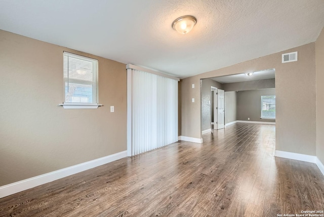 unfurnished room featuring dark hardwood / wood-style floors, a healthy amount of sunlight, and a textured ceiling