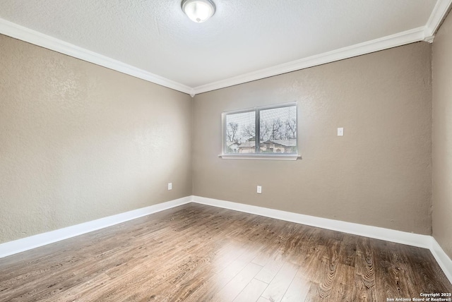 spare room with a textured ceiling, hardwood / wood-style flooring, and crown molding