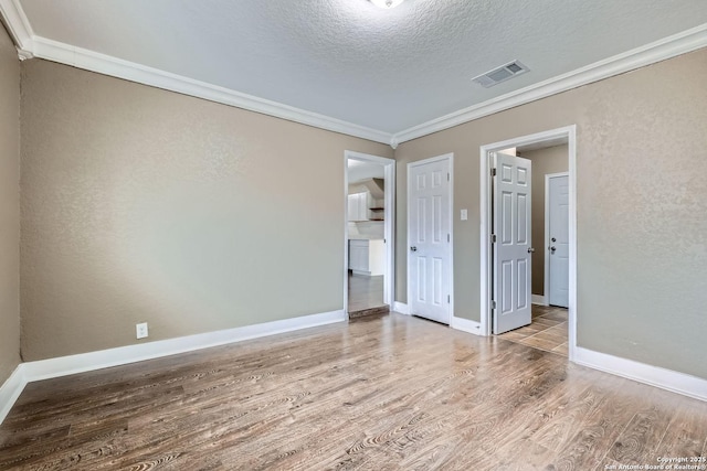 unfurnished bedroom featuring hardwood / wood-style floors, ornamental molding, and a textured ceiling