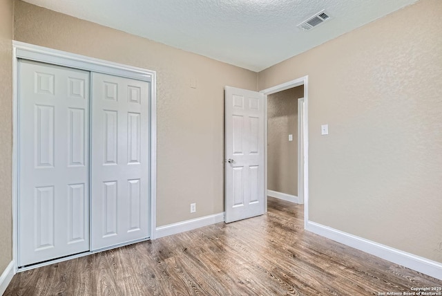 unfurnished bedroom featuring a closet, hardwood / wood-style floors, and a textured ceiling