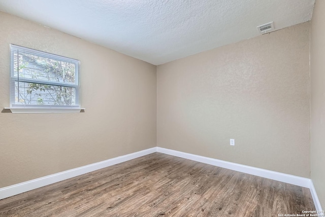 spare room with wood-type flooring and a textured ceiling