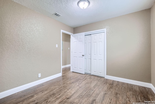 unfurnished bedroom with a closet, hardwood / wood-style floors, and a textured ceiling