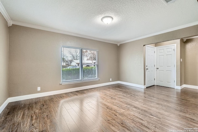 empty room with hardwood / wood-style floors, ornamental molding, and a textured ceiling