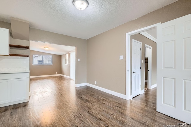 interior space with vaulted ceiling, dark hardwood / wood-style flooring, and a textured ceiling