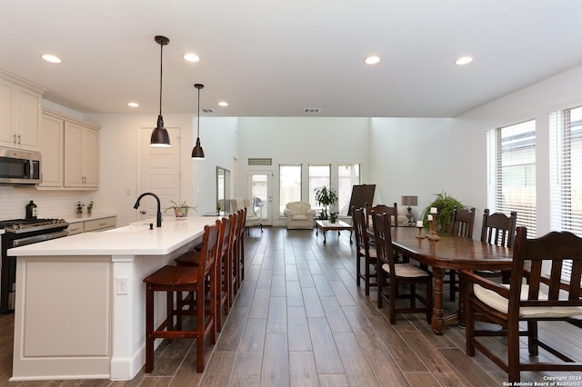 kitchen with black gas range, sink, decorative light fixtures, and a center island with sink