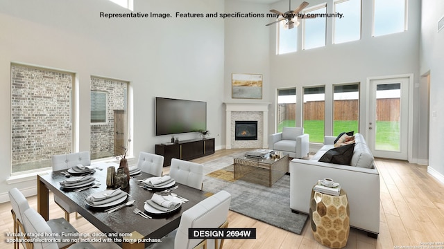 living room with ceiling fan, a towering ceiling, and light hardwood / wood-style flooring