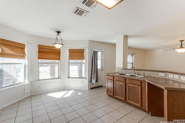 kitchen with ceiling fan, sink, light tile patterned floors, and decorative light fixtures