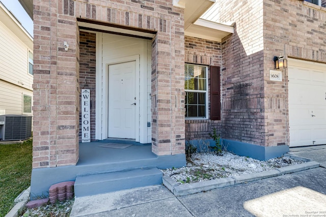 view of exterior entry featuring central AC unit and a garage