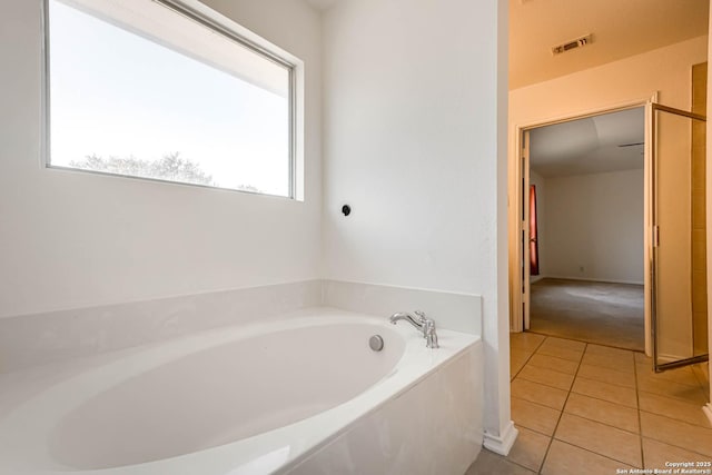 bathroom featuring tile patterned floors, a washtub, and a healthy amount of sunlight